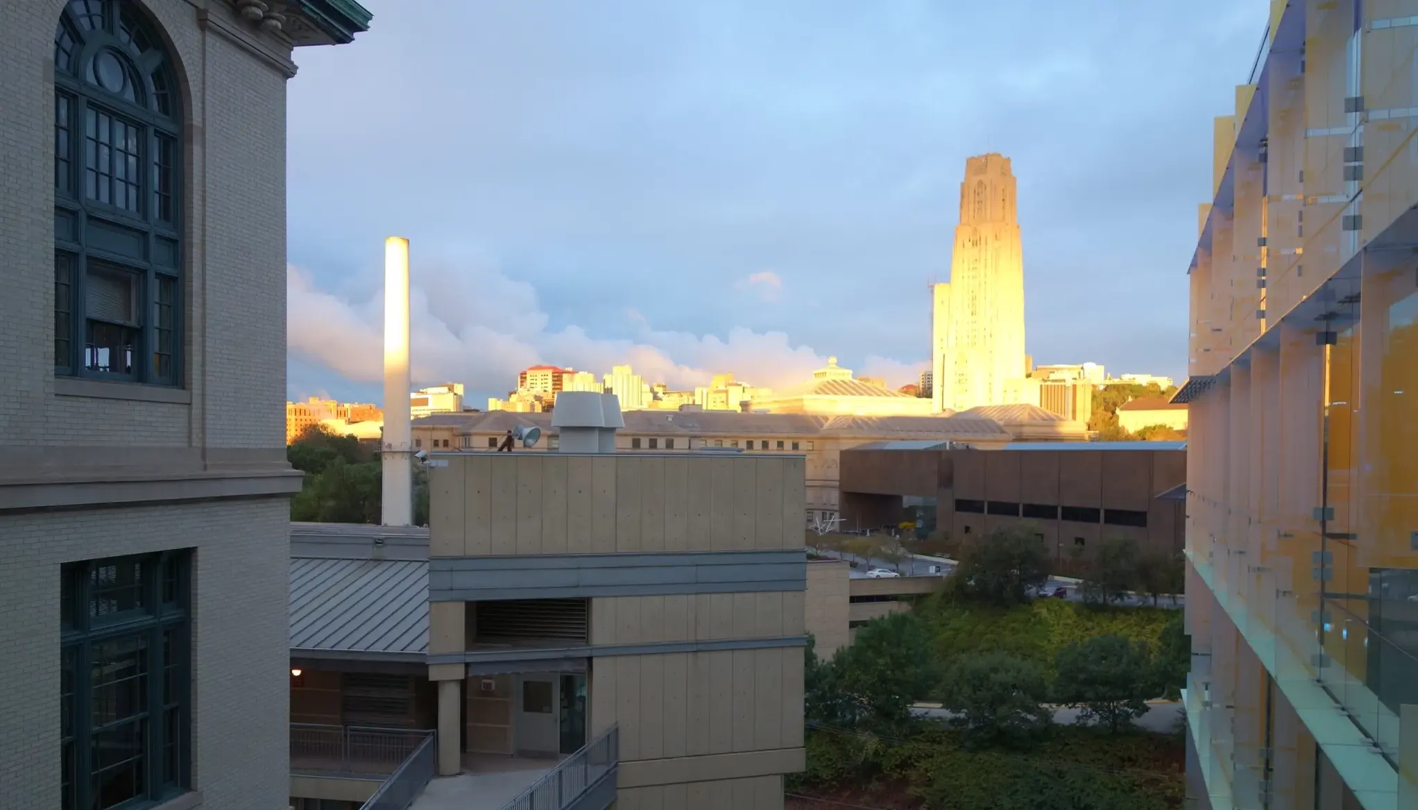 A photo of Carnegie Mellon University in the morning with the Cathedral of Learning in the background in the sun.