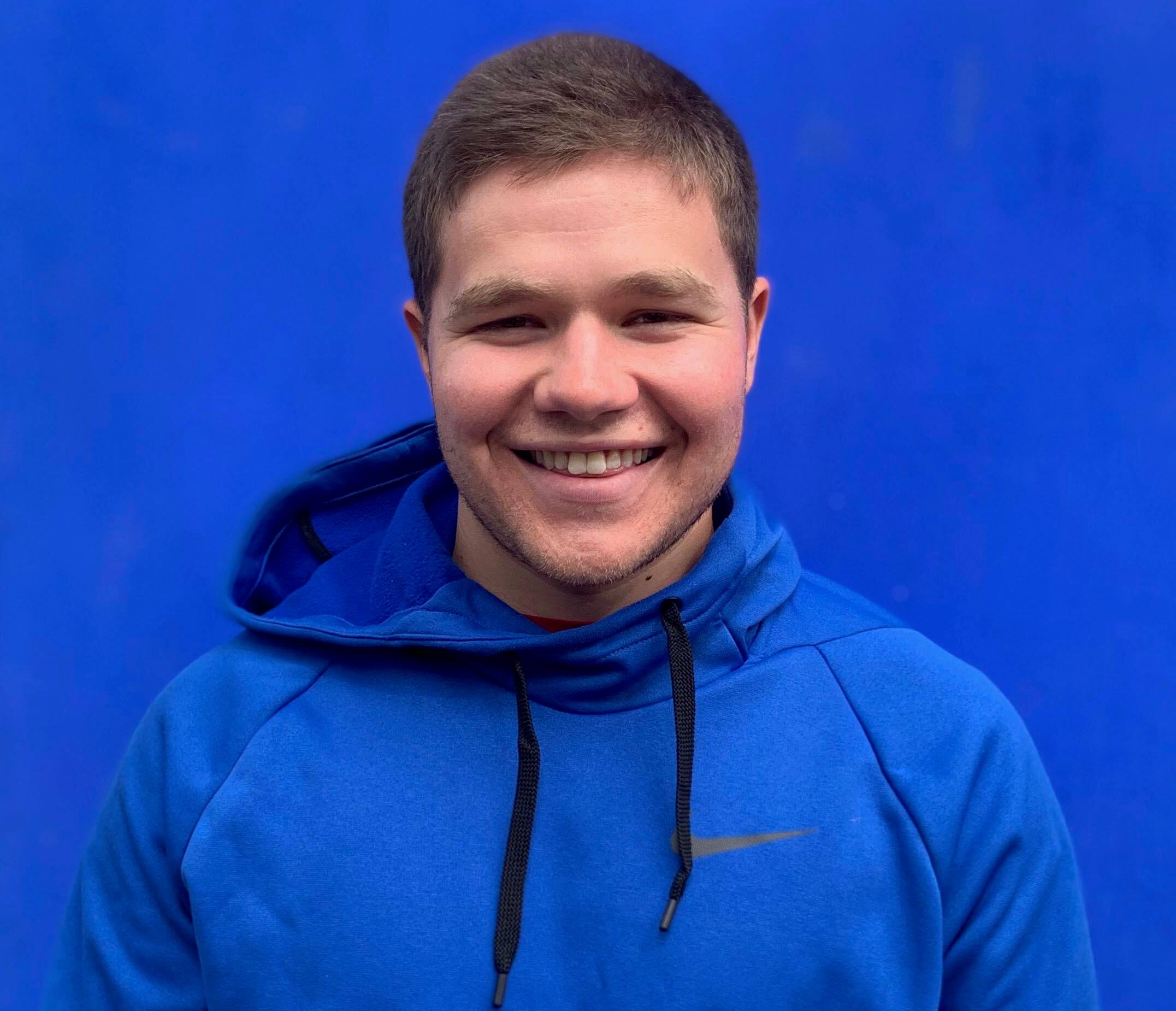 A picture of Rafael Goldstein in a blue hoodie in front of a blue wall.